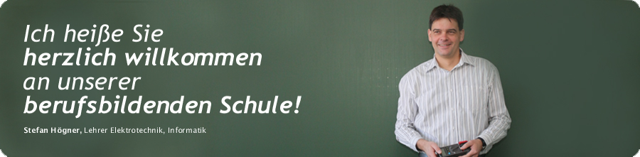 Fotografie einer Lehrerin/eines Lehrers vor gr�ner Tafel mit dem Text: Herzlich willkommen an unserer Berufsbildenden Schule.